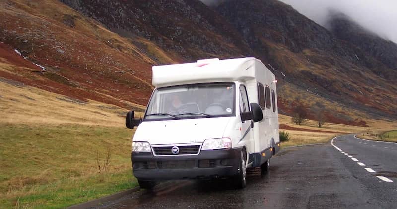 Motorhome driving a wet road through misty hills